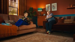 Man and woman smiling at each other sitting the sofa