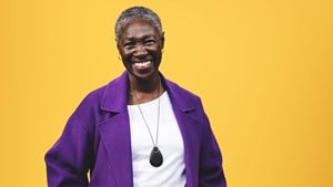 Smiling woman in purple coat wearing a black personal alarm pendant