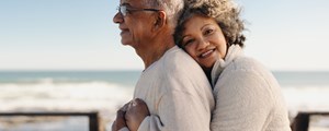 Senior woman embracing her husband by the ocean