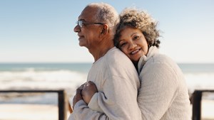 Senior woman embracing her husband by the ocean