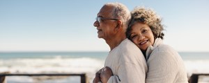 Senior woman embracing her husband by the ocean