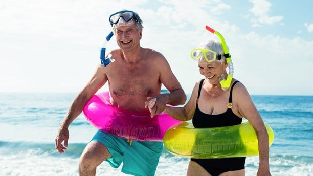 Older couple on the beach with rubber rings and snorkels