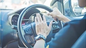 Hands at a car steering wheel pressing horn