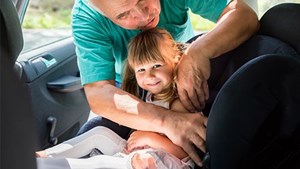 Little girl being buckled into car seat