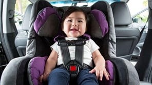 Small child strapped into purple car seat