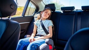 Young girl in booster seat snoozing in car