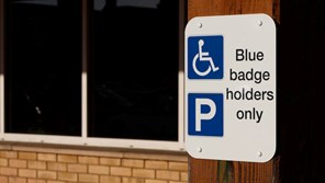 A disabled parking sign with blue badge mention