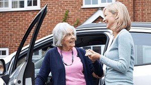 Older woman being assisted to get out of a car