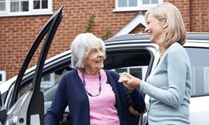 Older woman being assisted to get out of a car