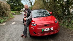 Older man next to his red electric car