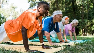 A older group of people doing yoga in the park