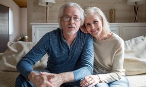 Relaxed looking older couple sitting on the end of their bed