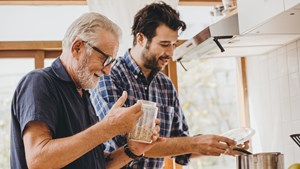 Adult father and son cooking together in a kitchen