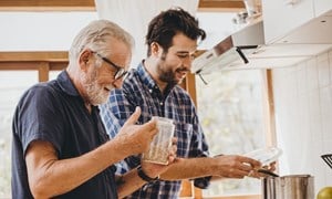 Adult father and son cooking together in a kitchen