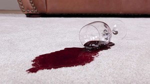 Spilled glass of red wine on a pale carpet