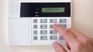 Person entering a code to activate the burglar alarm and protect their home