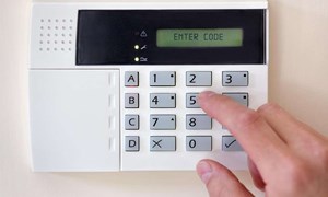 Person entering a code to activate the burglar alarm and protect their home