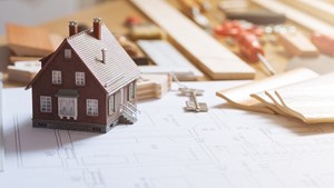 Model house on a workbench next to structural plans