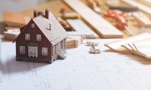 Model house on a workbench next to structural plans