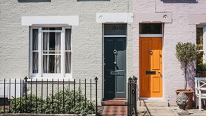 Fronts of two houses with one grey and one orange door