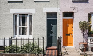 Fronts of two houses with one grey and one orange door