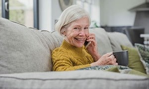 Older woman sitting talking on mobile phone with mug of tea