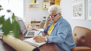 Woman on the phone at her desk and making notes in jotter