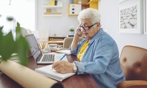 Woman on the phone at her desk and making notes in jotter