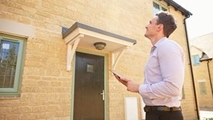 Surveyor standing outside a house surveying the property