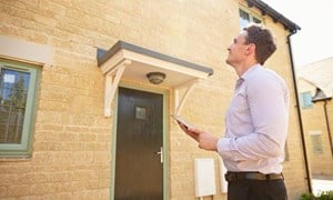 Surveyor standing outside a house surveying the property