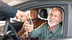 Couple in new car being handed the keys by a dealer