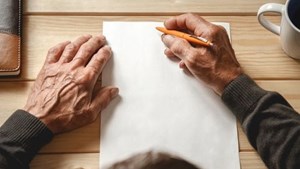 Close up of hands holding pencil about to write on a blank sheet of paper