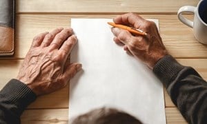 Close up of hands holding pencil about to write on a blank sheet of paper