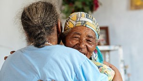 Elderly woman being embraced by carer