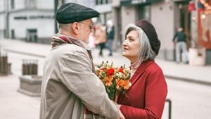 Older couple embracing in the street and holding flowers