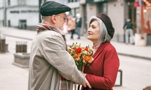 Older couple embracing in the street and holding flowers