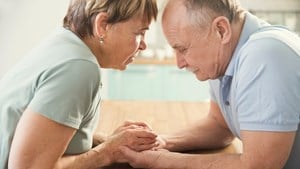 Anxious looking couple holding hands across a table