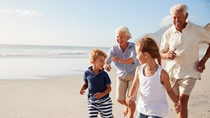 Grandparents and children running along beach