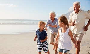 Grandparents and children running along beach