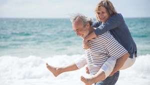 Man-giving-a-woman-a-piggy-back-on-the-beach_16.9