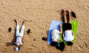 Three people laying on the sand